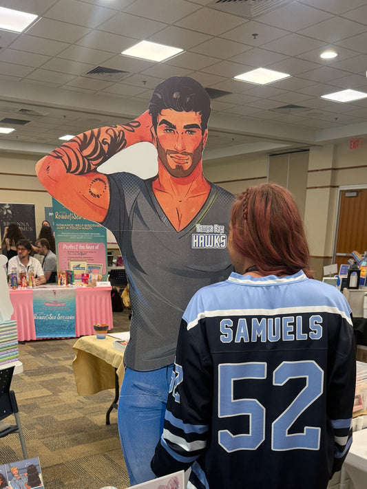 Person wearing a sports jersey with 'Samuels 52' at an event with books and promotional materials on a table.